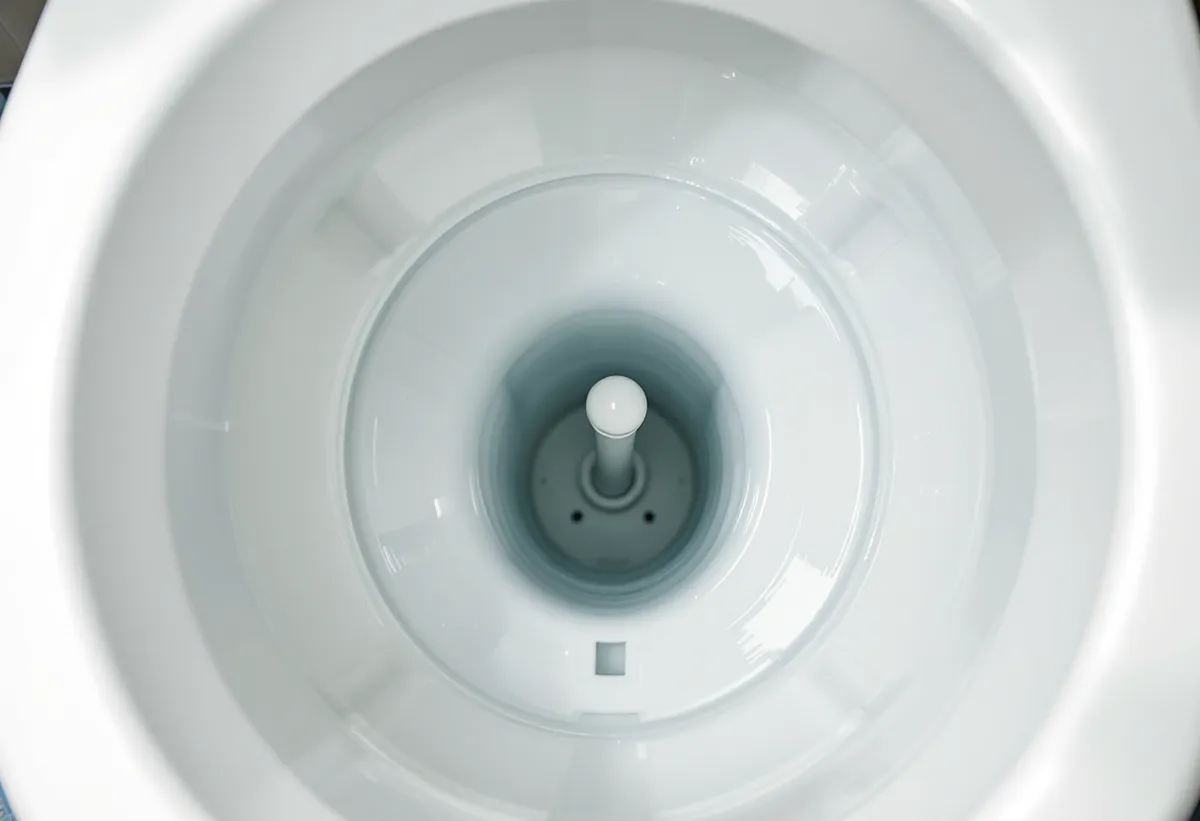 Interior de uma caixa acoplada de vaso sanitário mostrando o mecanismo de descarga
